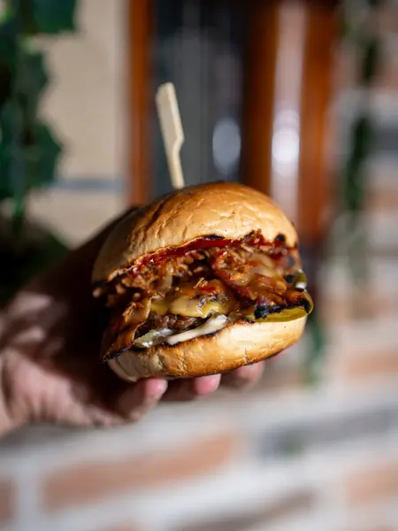 Burger sa slaninom u ruci gosta